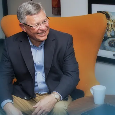 Bobby Albert seated in an armchair, smiling and looking off camera.
